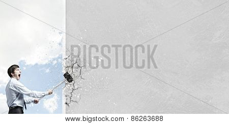 Young determined businessman with hammer in hands