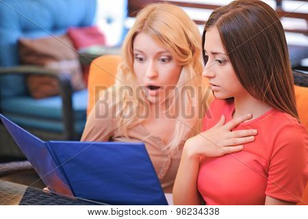 Two girls in cafe looking through menu