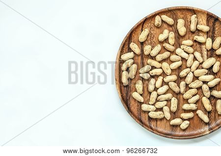 Roasted peanuts on wooden dish and white background