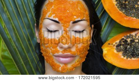 Beautiful caucasian Woman Having fresh Papaya natural facial mask apply. Papaya Peeling. Skin care and Wellness (outdoors). Facial vitamin mask of papaya slices at spa salon. Antioxidant cosmetic