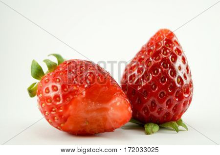 2 Strawberries have white background.One strawerry is eaten.You can see it closeup with macro.