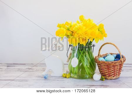 Easter eggs hunt - white rabbit, basket with painted eggs and daffodils bouquet