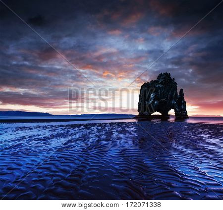 Hvitserkur is a spectacular rock in the sea on the Northern coast of Iceland. Legends say it is a petrified troll. On this photo Hvitserkur reflects in the sea water after the midnight sunset.