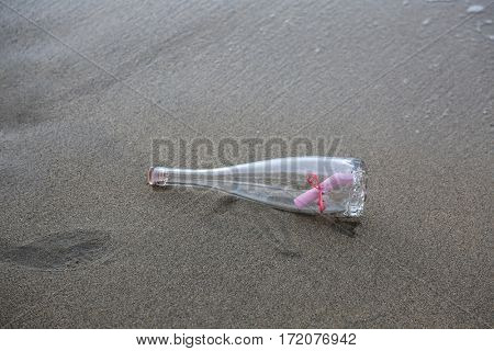 Message in a bottle. Romantic Love Note on Pink Paper with a Pink Ribbon in a wine bottle washed up on the shore in Maui Hawaii. Message of love. love notes.