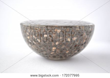 Gelled chia seeds (Salvia hispanica) in a glass and dry seeds in a bowl. Isolated on white.