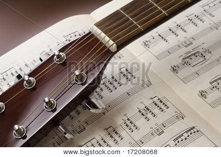 Chitarra close up sul foglio di musica di sottofondo