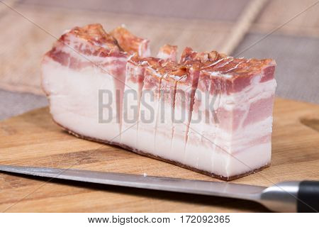 Piece Of Bacon With Kitchen Knife On The Wooden Board