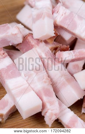 Sliced chopped bacon on the kitchen wooden board.