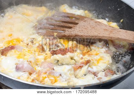 Frying eggs with sliced bacon in the hot oil.