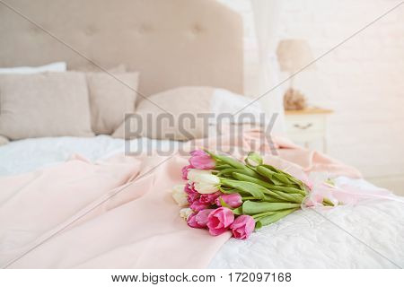 Nice bouquet with pink and white tulips lie on bed in the light room at the morning