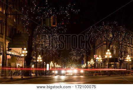 Vancouver Canada - January 28 2017: Gastown Vancouver at night with lights in the trees and light trails from the traffic.