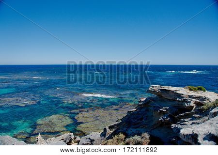 A rocky cliff overlooking the crystal blue sea