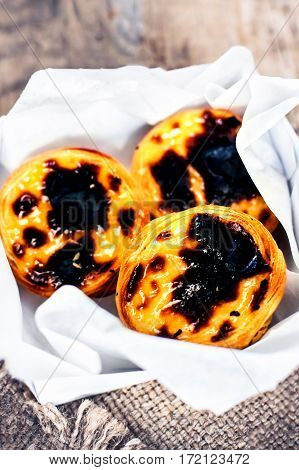 Pastel de Nata - creamy egg tart with sweet curstard black crust and sugar powder on wooden background. Pasteis de Belem pastry