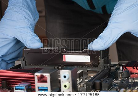 Close Up Of Man Hands With Gloves Installing Ram Ddr4 Memory Module In Slot On Motherboard