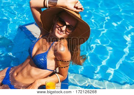 Beautiful Blonde Woman Wearing A Hat And Sunglasses, Enjoying The Pool