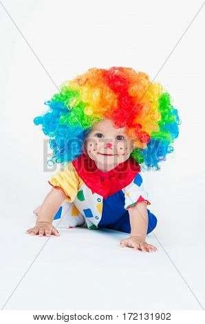 Children clown with a red nose multicolored wig in with balls. On a white background.