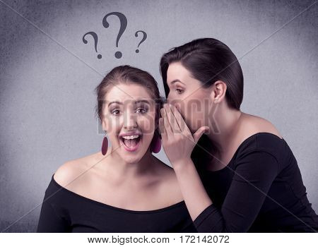 A teenager girl looking confused with drawn question marks above the head, while a girlfriend whispers something in her ear concept.