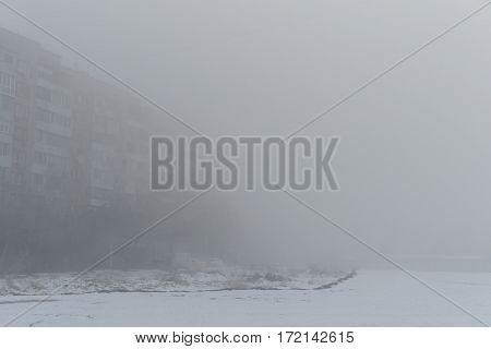 Foggy morning. Multi-storey building in the fog. Snowy morning and fog.