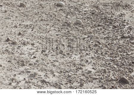 White arid cracked lumpy dry textured desert soil with brown black stones on slope from side