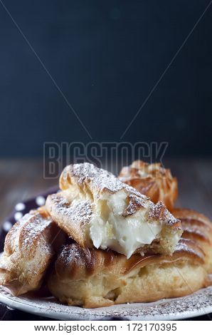 Tasty eclairs on wooden table close up