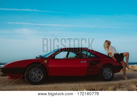 Young Beautiful Girl Sitting On Trunk Of The Red Ferrari