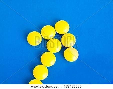 Arrow of yellow pills on a blue background