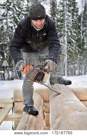 Leningrad Region Russia - February 2 2010: Log house building build a log house following the lateral lines with the chain saw creates a v- shaped cutout to house the lower log on the wall.
