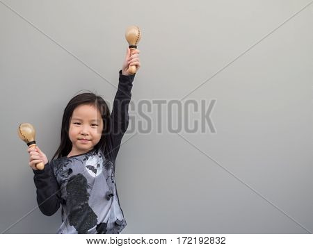 Little Asian Child Play The Maracas, Gray Background