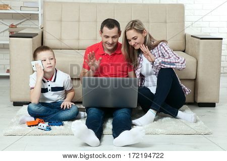 Family having fun chating on internet with laptop. Family having fun chating on internet with laptop. Three people communicate on Skype at home in living room.