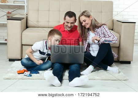 Family having fun chating on internet with laptop. Family having fun chating on internet with laptop. Three people communicate on Skype at home in living room.