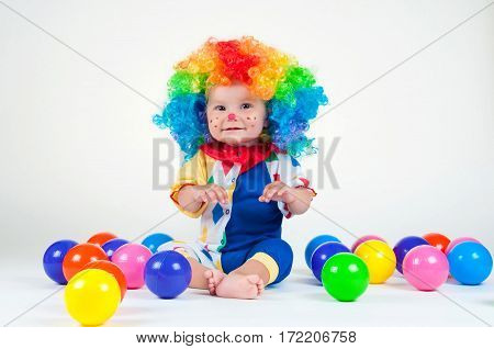 Children clown with a red nose multicolored wig in with balls. On a white background.
