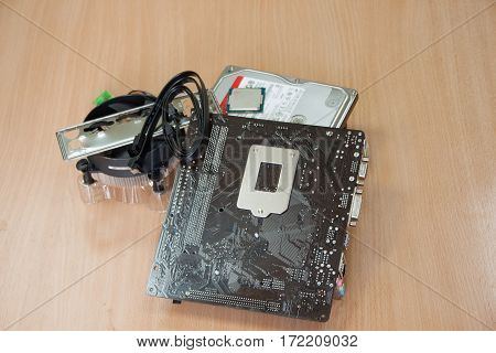 Group of accessories for assembly of personal computer on wooden table.