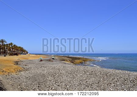 Playa De Las Americas beach Tenerife Canary Islands Spain Europe - June 12 2016: Pebble beach in Playa de las Americas Tenerife