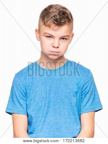 Teen boy making funny face. Half-length emotional portrait of child wearing blue t-shirt. Sad kid, isolated on white background.
