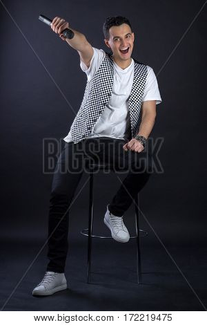 Young Male Black-haired Pop Singer Posing Singing To Microphone