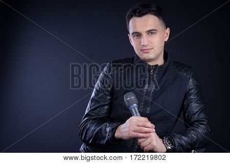 Young Male Black-haired Pop Singer Poses With Microphone