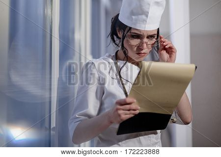 Female doctor in surgery reading patient notes