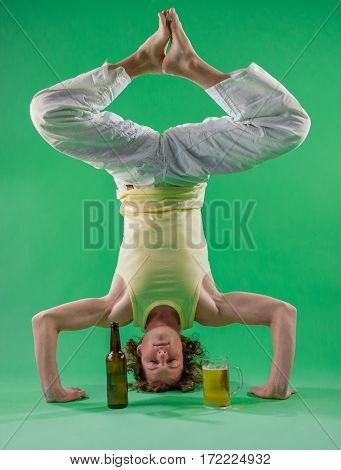 Caucasian man doing yoga with beer headstand pose