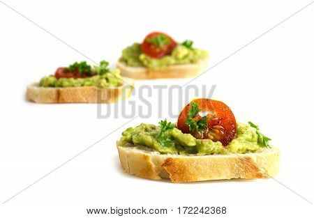 canapes with avocado cream or guacamole and tomatoes isolated on a white background healthy party sandwiches closeup selected focus narrow depth of field