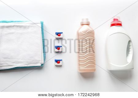 Bright towels pile with washing powder in laudry set on white table background top view