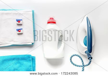 laundry set with bright towels and plastic bottels of detergent on white table background top view