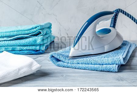 blue towels pile with iron in housekeeping set on laudry gray background