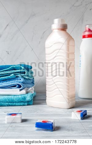 Pile of colorful clean towels with detergent on laundry gray background