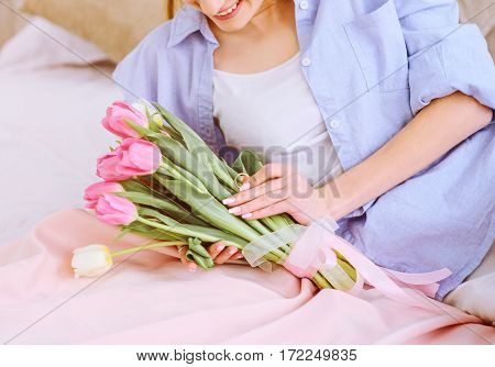 beautiful woman with white and pink tulips smiling on the bed