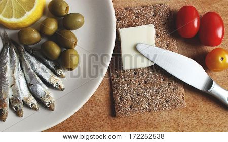 Saltde sprat ith lemon, olives, tomatoes, butter and bread