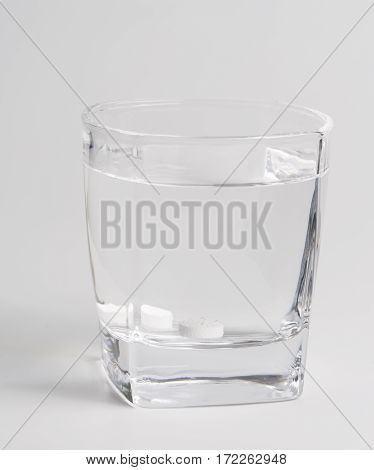 Round white pills and glass of water on a table waiting for eat