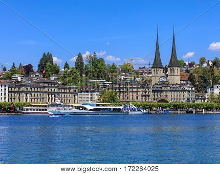 Lucerne, Switzerland - 8 May, 2016: people in boats on Lake Lucerne, buildings on National quay and towers of the Church of St. Leodegar in the background. The Church of St. Leodegar is a landmark of the city of Lucerne, Switzerland.