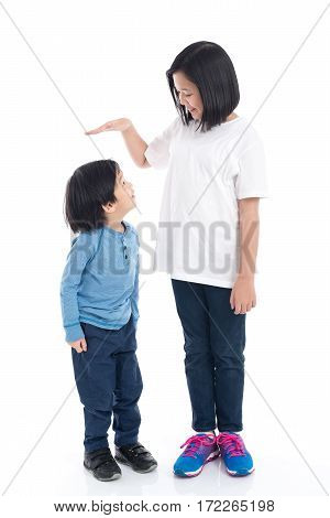 Asiangirl measures the growth of her brother on white background isolated