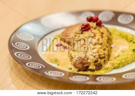 Meat patties or frikadeller in chese and mushroom sauce decorated with berries