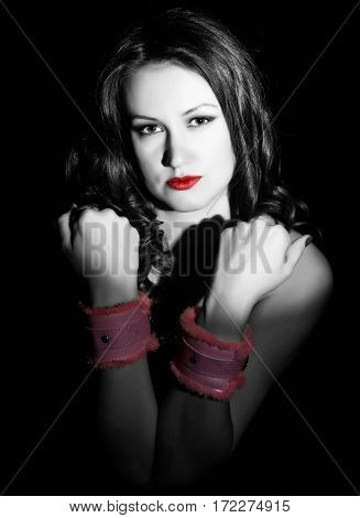 Sexy girl with a naked body and handcuffs posing in the studio on a dark background.